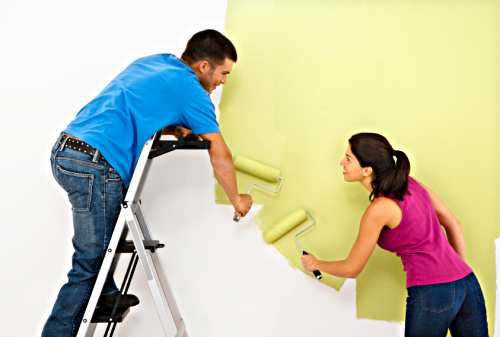 有吸引力的年轻夫妇粉刷房子的内墙。